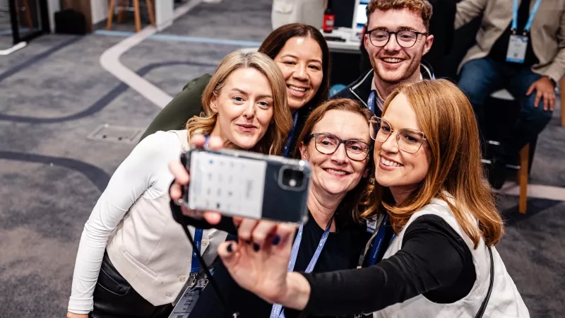 A group of people are taking a selfie in the hall with a smile on their faces.