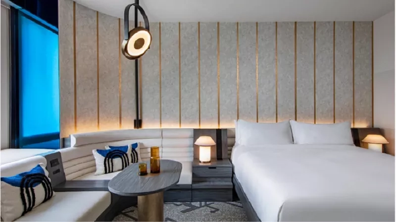A chic hotel room with white furniture, a sofa, a round table, and a king-sized bed.