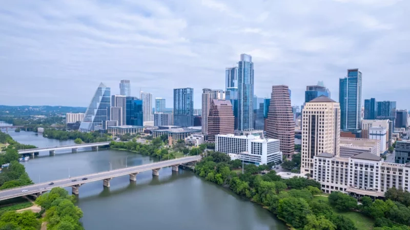 A top-angle view of Austin's skyline and Lady Bird Lake, showcasing modern architecture and lush landscaping.