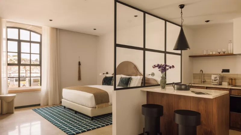 The bedroom at The House of Sandeman with a bed, kitchen, and windows.