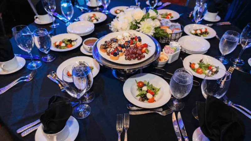 A dining table with round plates, wine glasses, and cutlery set for a meal in a restaurant.