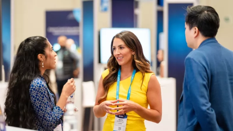 Woman and two men are talking in a conference room at the 2022 SAP Sapphire conference.
