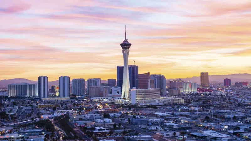 Las Vegas city skyline at sunset with the Stratosphere Tower and various buildings in view.