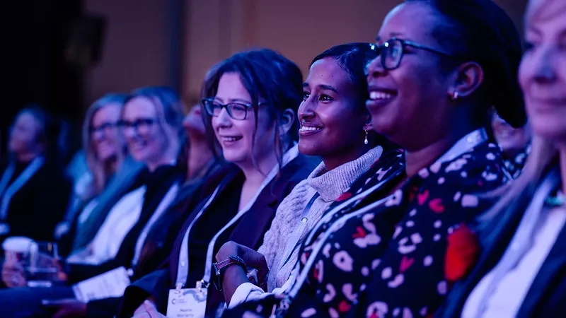 Three smiling women at an event, with event personalization.