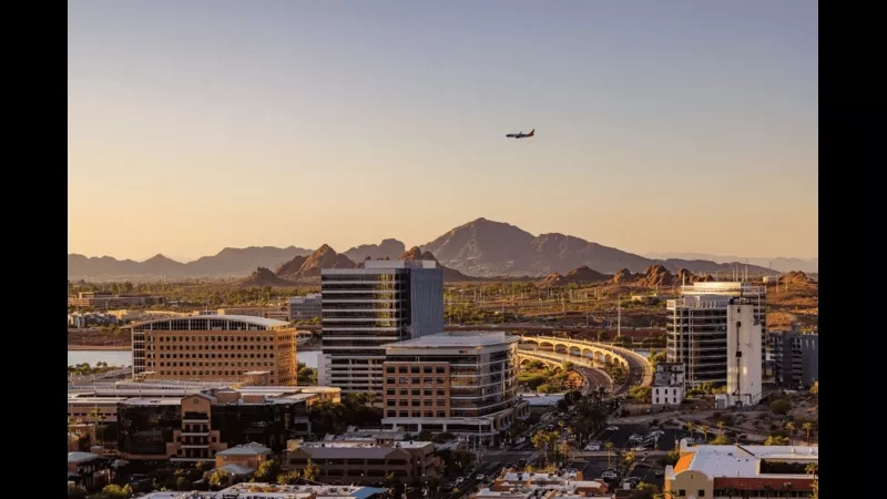 Airplane flying over cityscape of Phoenix with mountains and clear sky at dusk, Arizona.