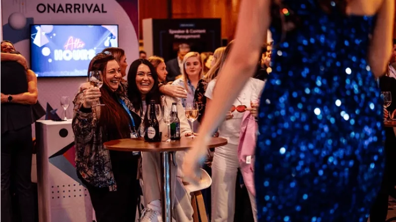 People at an event with a large ONARRIVAL sign and monitor displaying After Hours.