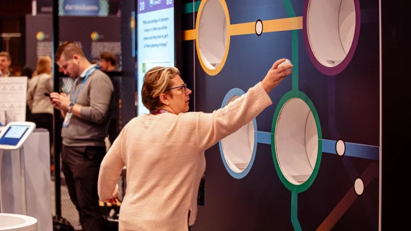 Woman throwing a ping pong ball into a hole at an interactive event entertainment game at Cvent CONNECT Europe 2024.