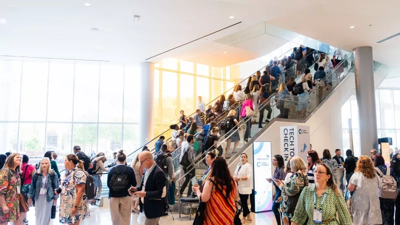 Several people are gathered at Cvent CONNECT Europe 2024 with a glass architecture and a crowd of people.