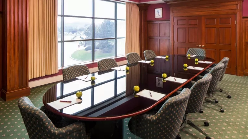 The Desmond Conference Room has a large oval table, green carpet, and a large window overlooking the lawn.