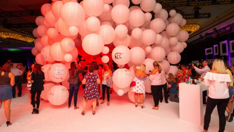 People at a Cvent event in a ballroom with a wall of pink lanterns.