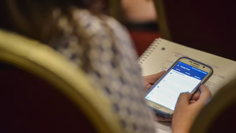 A woman is using her phone and looking at the screen in the Activity Feed section.