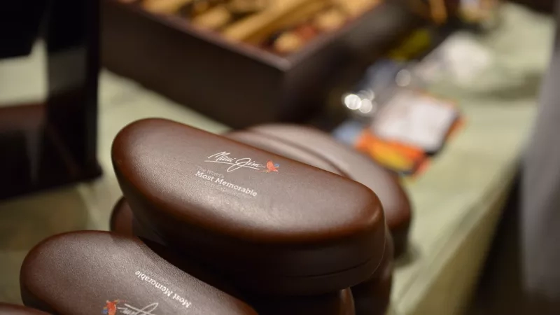 Brown leather cases with a brand logo on a table next to a wooden box and other items.