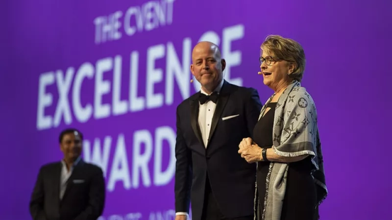 Three people on stage with the words "The Cvent Excellence Award" on a purple background behind them.