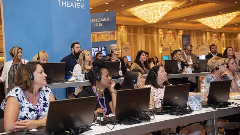 Several people are sitting in front of laptops on a table with a sign that reads "FEATURE FLASH THEATER."