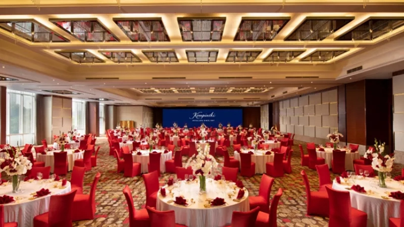 Kempinski Hotel Huizhou conference hall with large screen and many round tables and chairs.