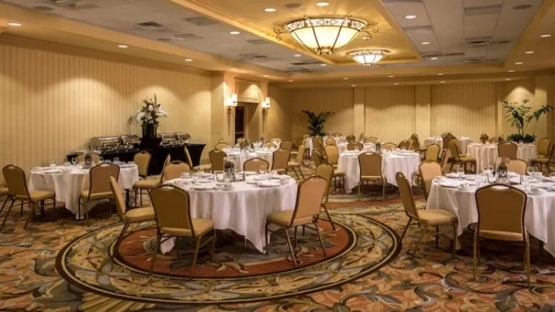 A spacious banquet hall with multiple tables and chairs, chandeliers, and elegant decor at the Four Seasons Hotel.