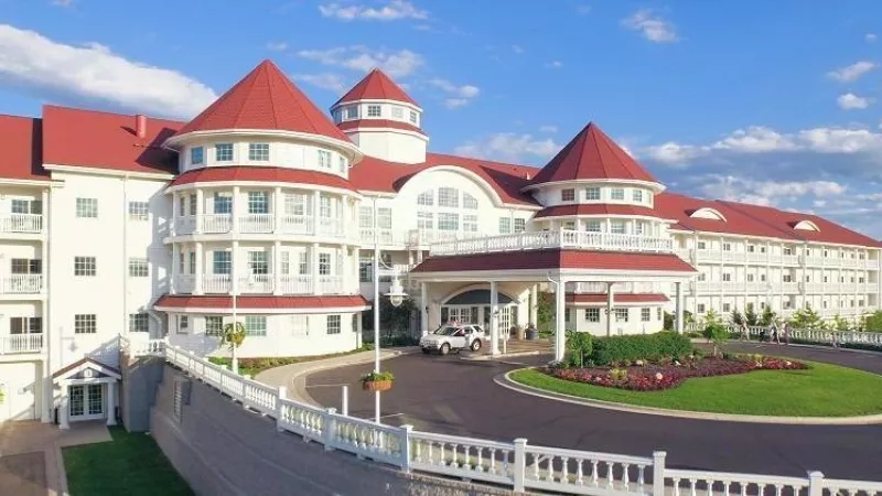 Exterior of Blue Harbor Resort with red roofs, white railings, and a white car in the driveway.