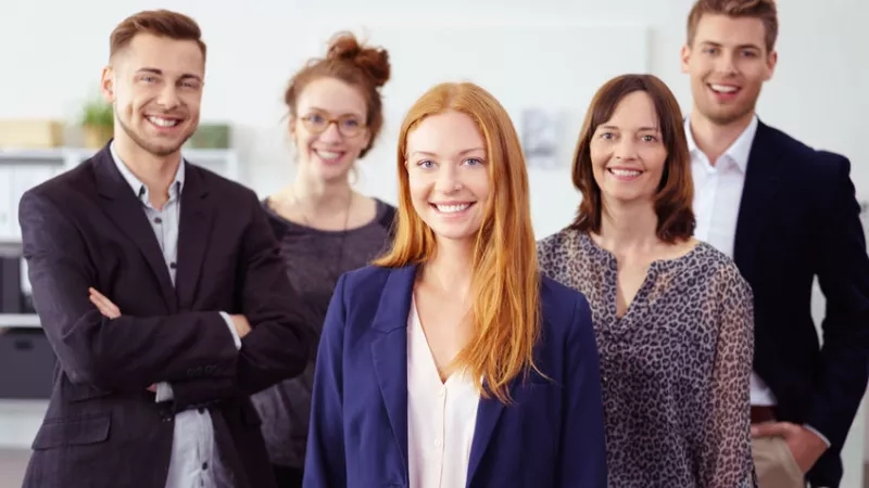 A group of four people are standing in a room and posing for a photo with smiling faces.