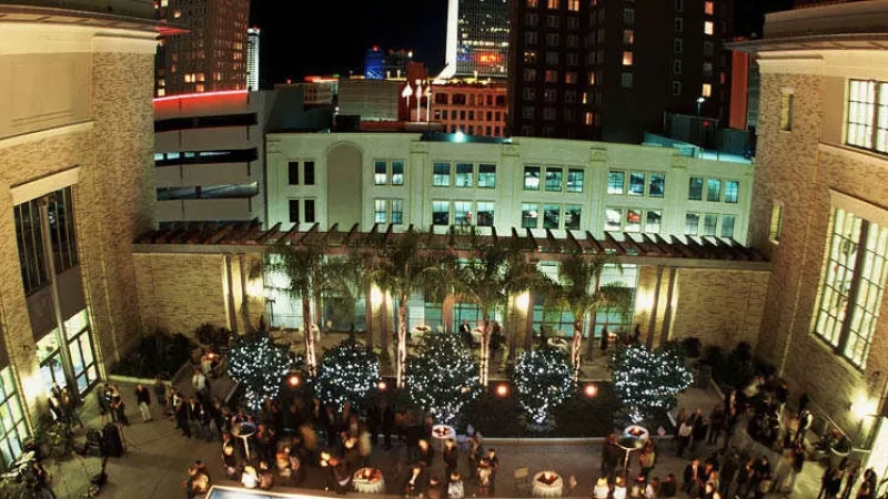 A nighttime aerial view of the courtyard with lights and buildings in the background.