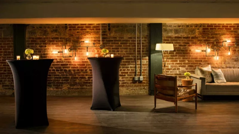 A cozy room with a couch, a chair, and two black tables with candles on top.