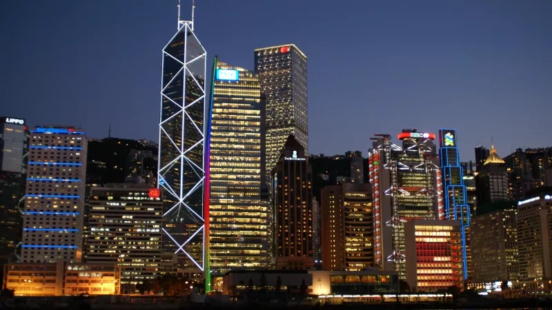 A group of tall buildings with colorful lights at night in Central, Hong Kong.
