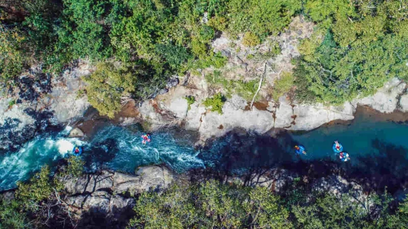 Aerial view of people floating down the river on a raft in Costa Rica, with lush forest around.