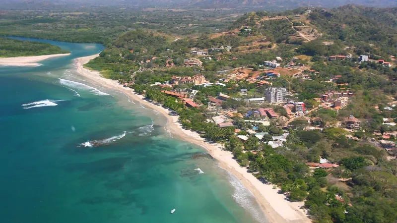 Aerial view of Playa Tamarindo and Rivermouth in Costa Rica with a white boat in the water.
