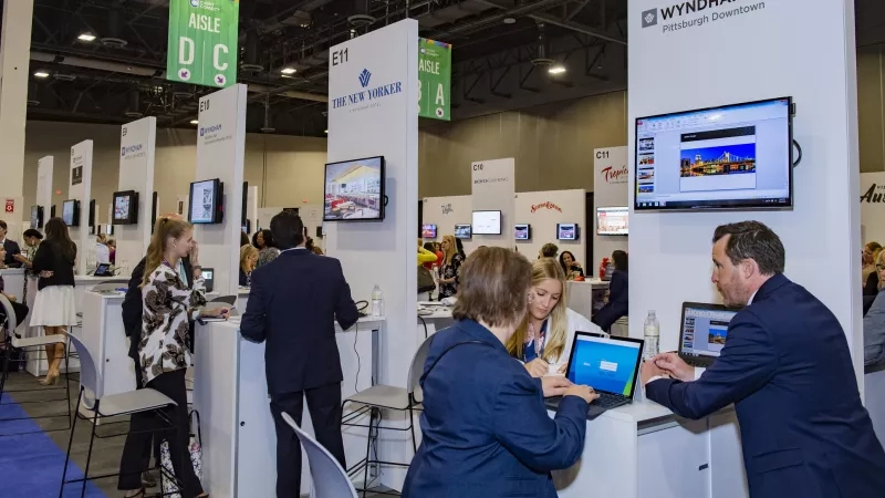 People looking at screens at the Wyndham Downtown Pittsburgh booth at the Cvent CONNECT 2018 trade show.