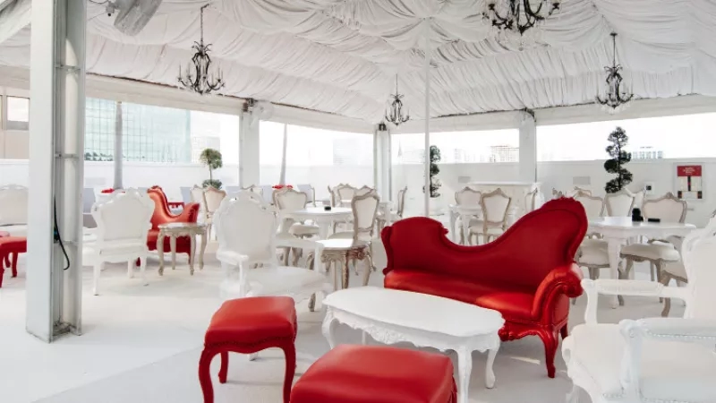 Red and white chairs and tables are arranged in the outdoor space of the Delano South Beach Hotel.