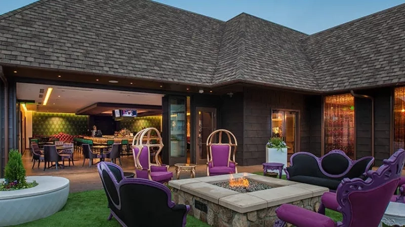 A luxurious outdoor lounge area at night with purple chairs, fire pit, and elegant decor at Ciel Spa.