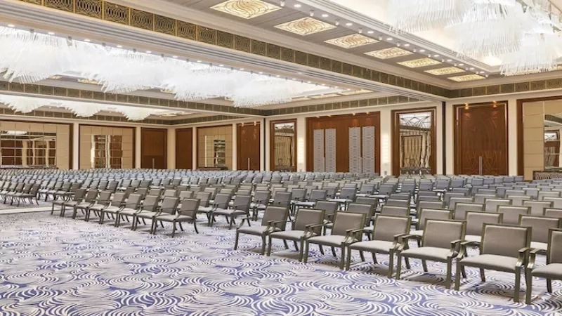 Large ballroom at Al Joud Boutique Hotel with rows of chairs and chandeliers on the ceiling.