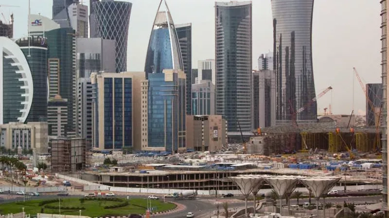 Cityscape of Doha, Qatar, with a view of modern architecture, roads, and lush green lawns on a foggy day.