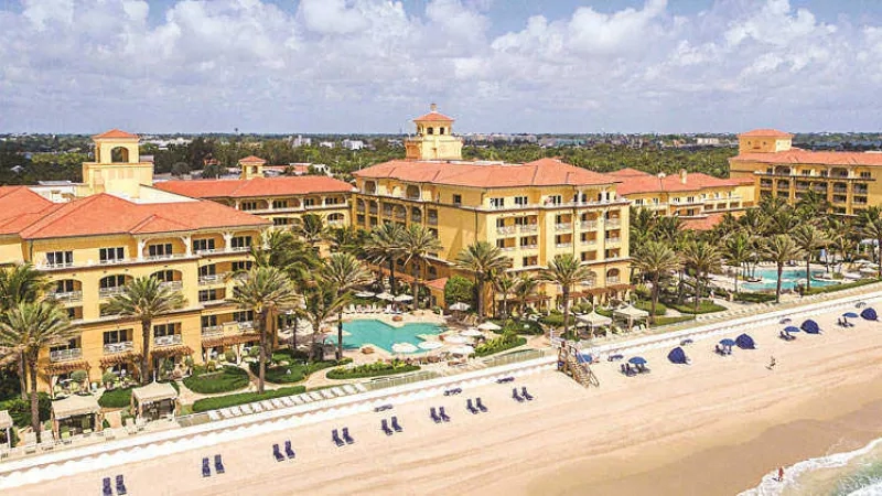 A resort with a beach, swimming pool, and many chairs on the beach for a relaxing stay.