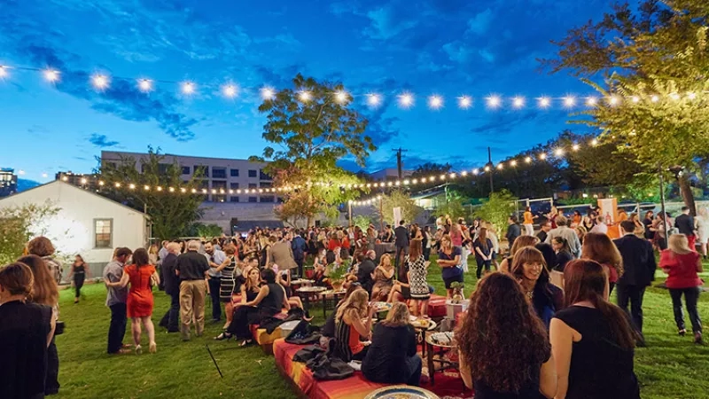 A large crowd of people at Fair Market in Austin, Texas, with string lights and outdoor seating.