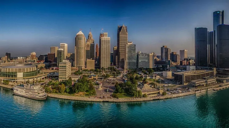A stunning panorama of the Detroit skyline, featuring towering buildings, a serene river, and lush greenery.