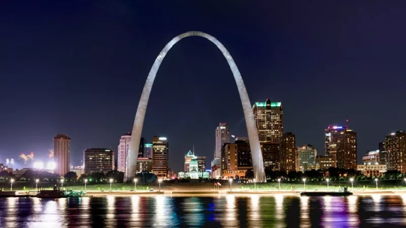 The Gateway Arch in St. Louis at night with the city skyline in the background.