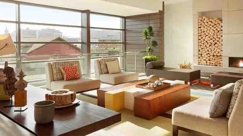 Modern living room with a large glass wall, fireplace, and furniture in the August 2017 featured article.