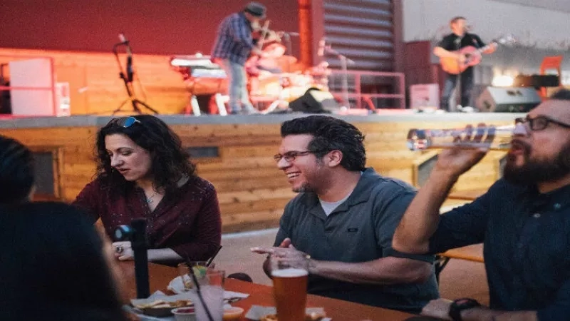 Four people sit at a table and watch a band play on stage at The Coffee House.