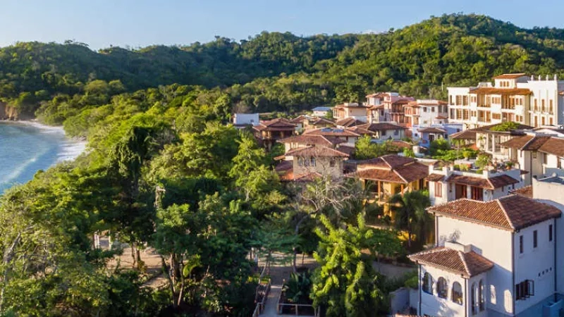 Aerial view of El Mangroove featuring architecture, landscaping, and ambiance with blue sky and ocean in background.