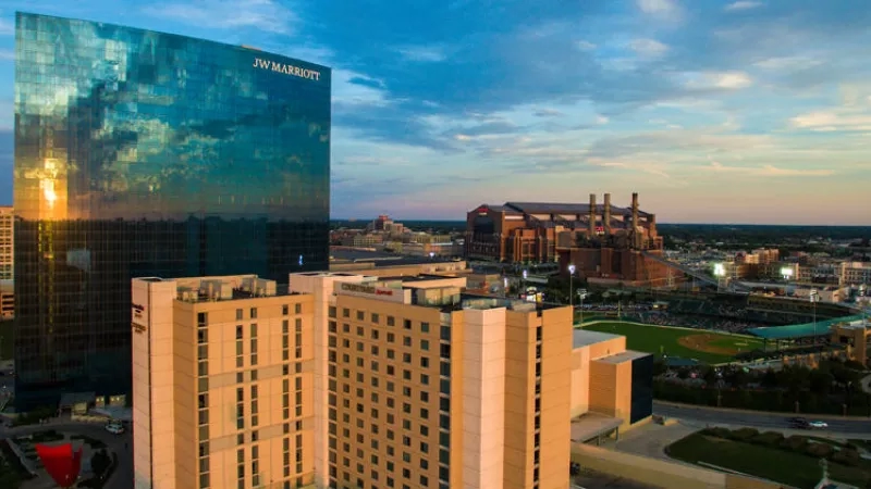 JW Marriott Milwaukee hotel exterior, cityscape, glass building, and a baseball stadium at sunset.