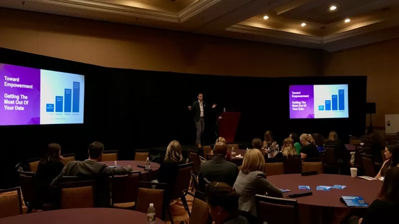 A man is giving a presentation in front of an audience in a conference room.