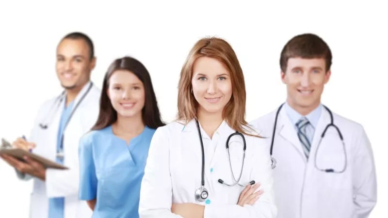 A group of health care professionals stand in a row with a white background.