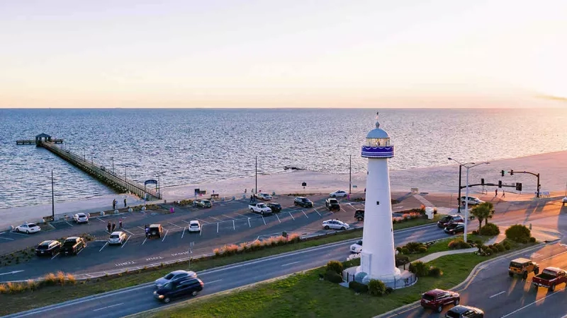 Aerial view of the Mississippi Gulf Coast with cars and a lighthouse by the beach.