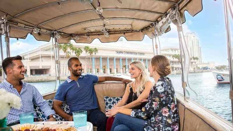 Group of four people on a boat with the Tampa Convention Center in the background.