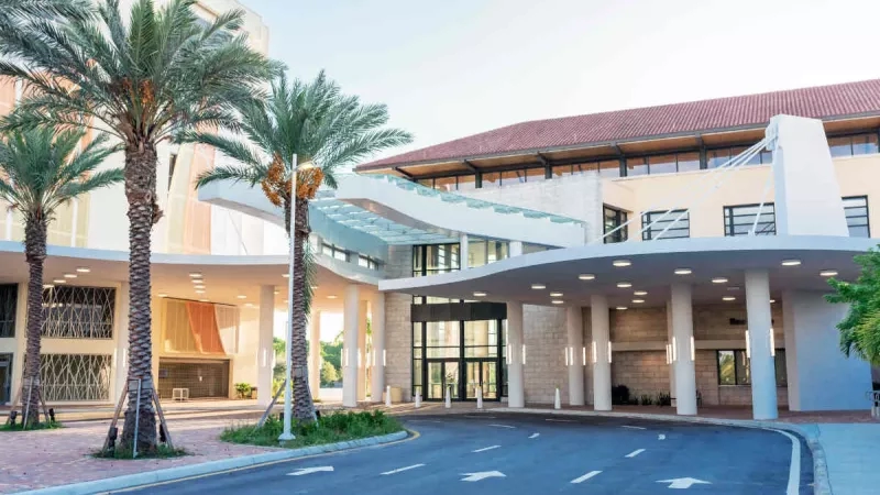 Discover the Palm Beaches with a modern building, palm trees, and a paved driveway.