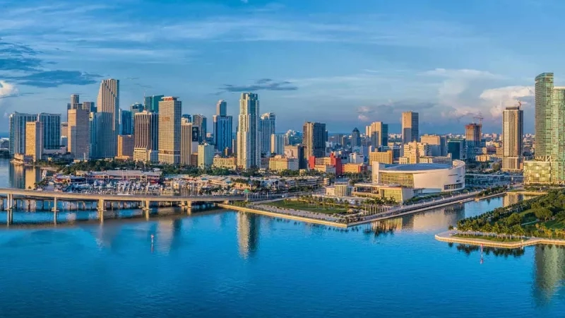 Miami skyline with blue water in the foreground and high-rise buildings in the background.