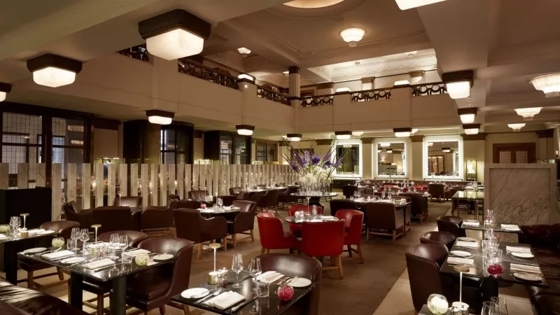 Hotel Cafe Royal interior view of the restaurant with tables and chairs and flower centerpieces on the tables.