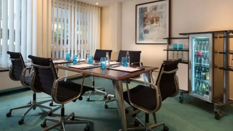 Meeting room with a desk, chairs, and refreshments, with a picture on the wall at Kempinski Hotel Bristol.