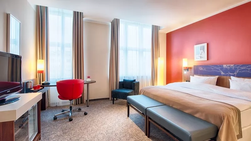 Leonardo Royal Hotel Berlin Alexanderplatz, a room with a bed, desk, TV, and chair.
