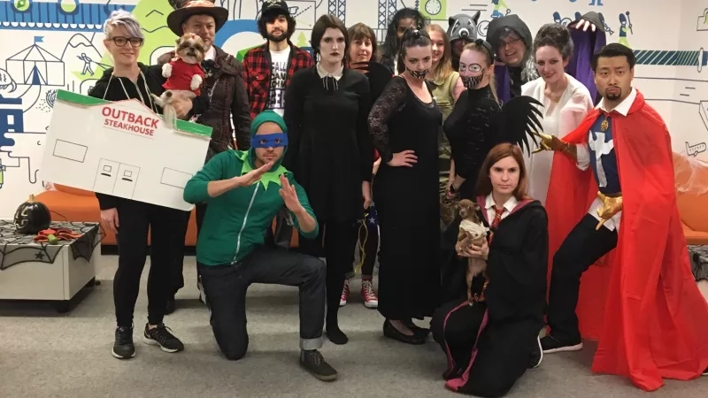 Group of people in cosplay costumes posing for a photo in front of a colorful wall.
